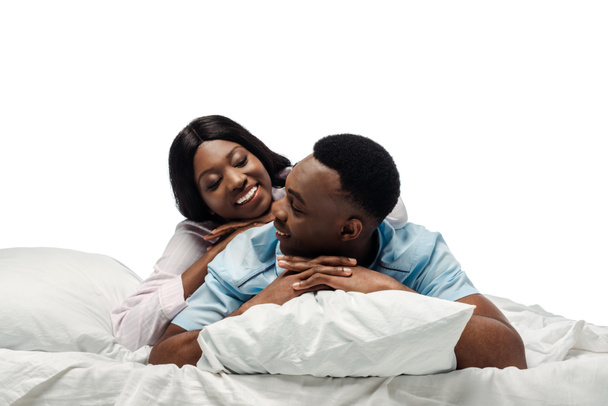 glücklich afrikanisch-amerikanisches Paar liegt im Bett im Pyjama isoliert auf weiß - Foto, Bild