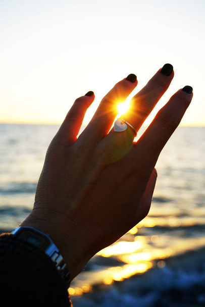 ręka dziewczyny na brzegu morza o zachodzie słońca - Zdjęcie, obraz