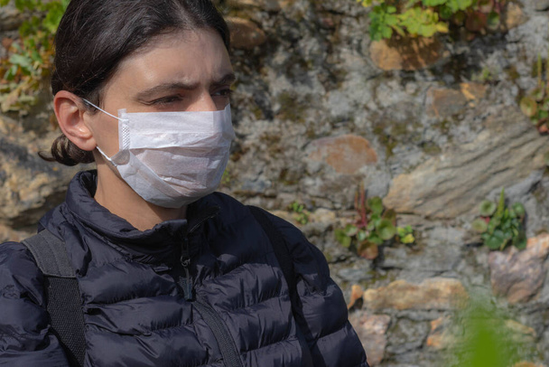 Γυναίκα κοιτάζει προς τα δεξιά με προστατευτική μάσκα στο πρόσωπό της κατά τη διάρκεια της επιδημίας του ιού. - Φωτογραφία, εικόνα