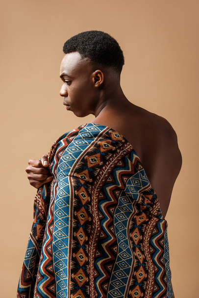 sexy naked tribal afro man covered in blanket posing isolated on beige - Fotografie, Obrázek