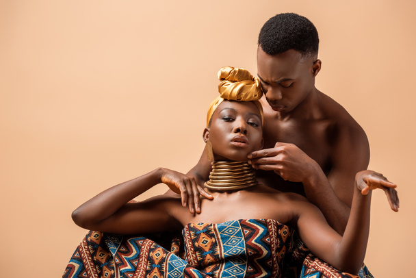 sexy naked tribal afro woman covered in blanket posing near man isolated on beige - Foto, Imagem