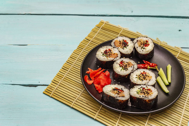 Korean roll Gimbap(kimbob). Steamed white rice (bap) and various other ingredients. Trendy turquoise wooden boards background - Photo, Image