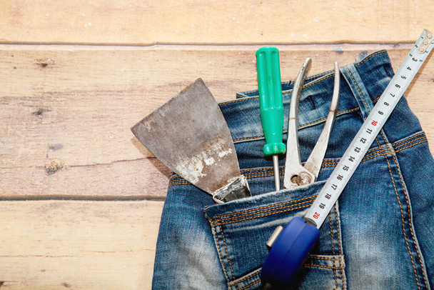 Top view tools in in blue jeans pocket a wooden background. Engineering concept style - Fotoğraf, Görsel