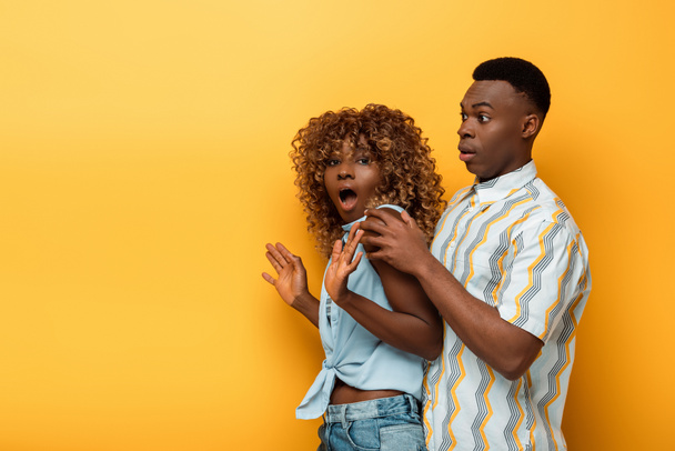 side view of scared african american couple on yellow colorful background - Photo, Image
