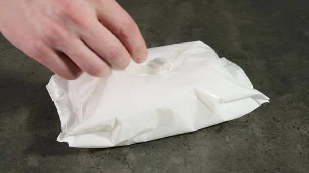 Hand takes wet antibacterial napkin out of packaging. Close up. - Фото, зображення