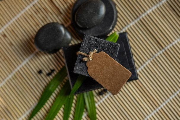 charcoal coal carbon black soap bar on a raw wood bamboo background lava stone spa skin care hygiene concept. black black stone backgroun. raw wood background lava stone spa skin care hygiene concept - Photo, Image