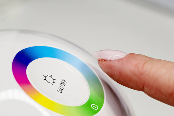 Woman finger turning off the light. Pressing index finger on lighting switch. Energy saving concept. - Photo, Image
