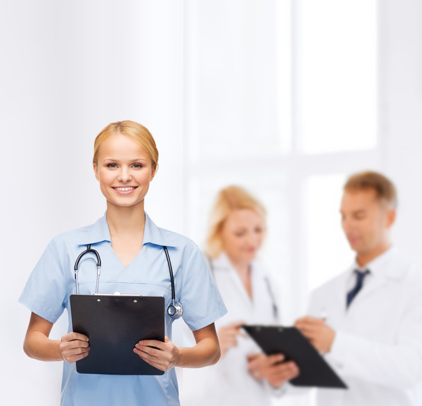 Smiling female doctor or nurse with clipboard - Fotó, kép