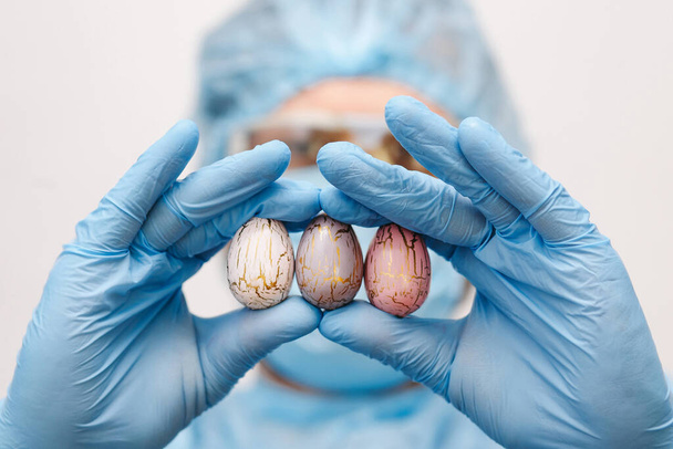 Hands in medical gloves holding modern painted easter eggs. Selective focus. Toned picture. - Фото, изображение
