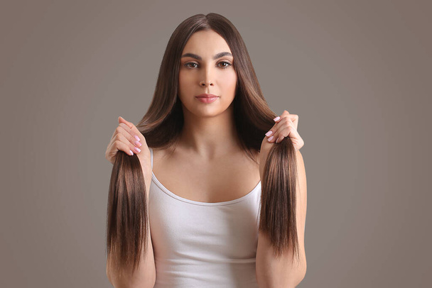 fiatal nő gyönyörű egyenes haj szürke háttér - Fotó, kép