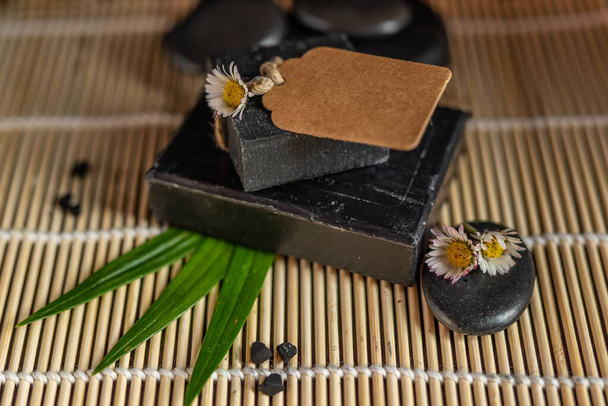 charcoal coal carbon black soap bar on a raw wood bamboo background lava stone spa skin care hygiene concept. black black stone backgroun. raw wood background lava stone spa skin care hygiene concept - Photo, Image