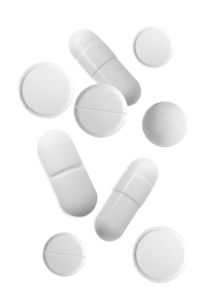 Diferentes píldoras que caen sobre fondo blanco
 - Foto, Imagen