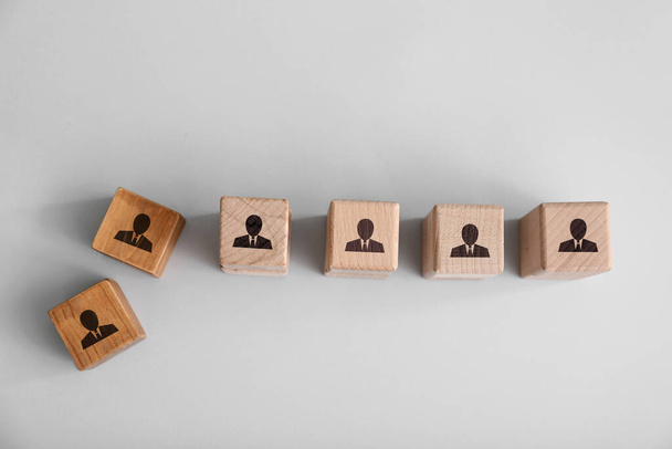 Cubes en bois avec des figures humaines dessinées sur fond gris. Notion de licenciement
 - Photo, image