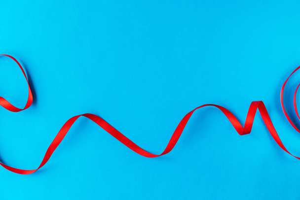 Wavy red ribbon on a blue background. A good idea for a holiday card or background for text, like a computer wallpaper or a screensaver on your phone - Photo, image