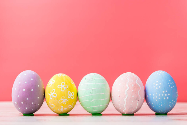 різнокольорові ручні розфарбовані яйця і прикрашені вдома на рожевому фоні. Великодня традиція
 - Фото, зображення