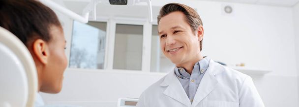 panoraama laukaus onnellinen hammaslääkäri katselee afrikkalainen amerikkalainen potilas
  - Valokuva, kuva