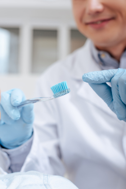 selective focus of dentist pointing with finger at toothbrush  - Foto, imagen