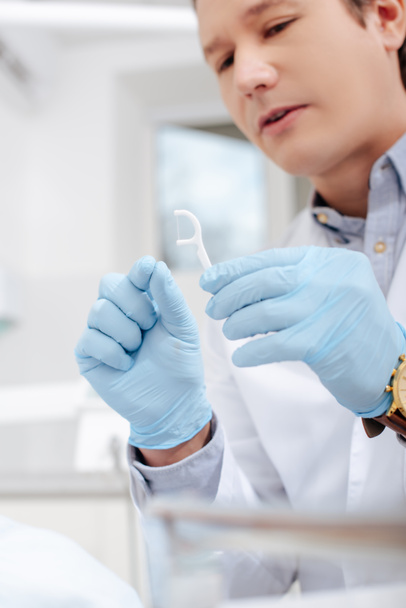 selective focus of dentist in latex gloves holding floss stick  - Photo, Image