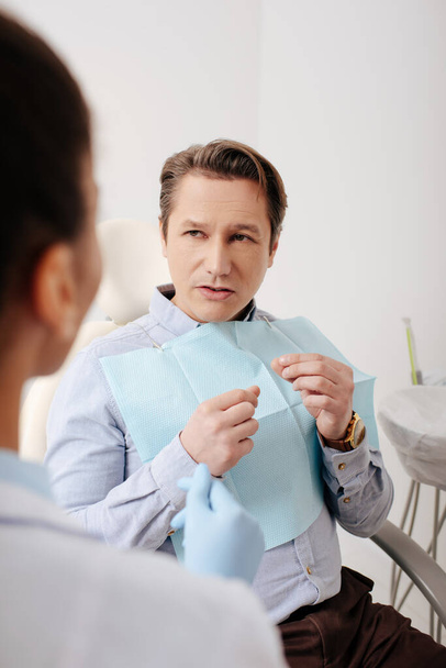 selective focus of man looking at african american dentist in clinic  - Foto, Bild
