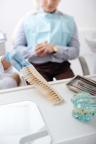 enfoque selectivo del dentista en guante de látex tomando paleta de dientes cerca del paciente
  - Foto, Imagen