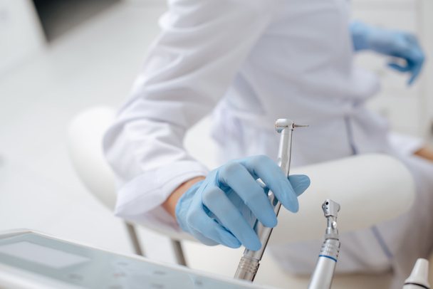 cropped view of dentist taking stainless dental instrument  - Фото, зображення