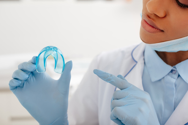 Ausgeschnittene Ansicht eines afrikanisch-amerikanischen Zahnarztes, der mit dem Finger auf Halter zeigt  - Foto, Bild