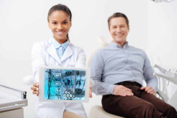 szelektív fókusz vidám afro-amerikai fogorvos gazdaság digitális tabletta orvosi alkalmazás a képernyőn közel boldog beteg  - Fotó, kép