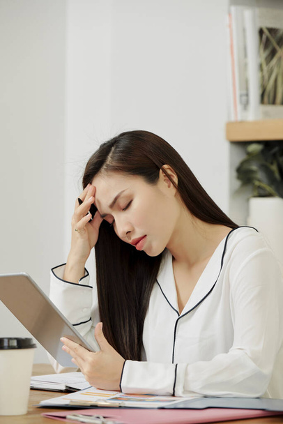 Stressed young female manager having headache after working on project all day long - Foto, imagen
