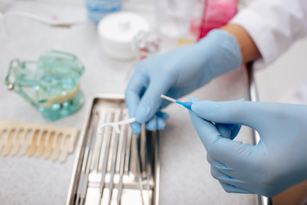 cropped view of dentist in latex gloves holding inter dental cleaning brush  - Photo, Image