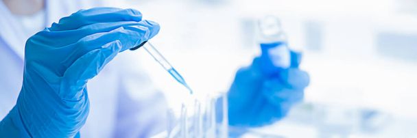 Medizinischer oder wissenschaftlicher Forscher oder Arzt, der in einem Labor ein Reagenzglas mit klarer Lösung betrachtet - Foto, Bild