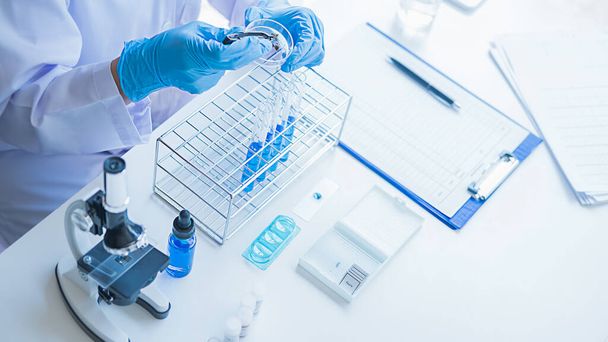 Медицинский или научный исследователь или человек врач, глядя на пробирку с чистым раствором в лаборатории - Фото, изображение