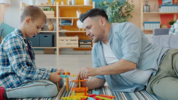 Happy family father and child playing with bright toys at home sitting on floor together - Imágenes, Vídeo