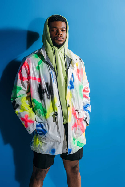 fashionable african american man posing in colorful futuristic look on blue - Photo, Image
