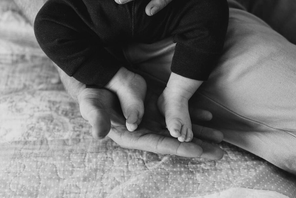 De benen van een pasgeboren close-up. Zwart-wit foto van de benen van een pasgeborene. - Foto, afbeelding