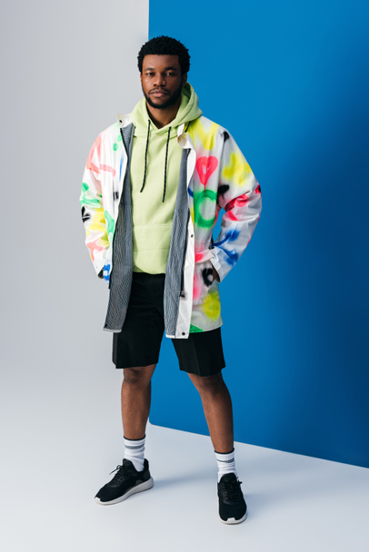 fashionable african american man posing in colorful futuristic clothes on grey and blue - Valokuva, kuva