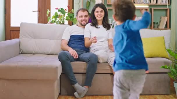 Two kids have a fun time with their young parents while sitting on the sofa the kids running to the parents they hugging each other and enjoying the time in the family. Shot on ARRI Alexa Mini - Кадри, відео