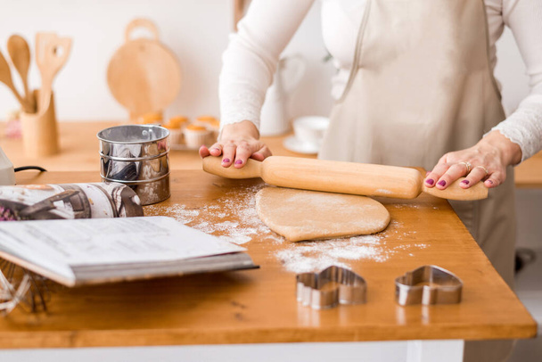Las manos de las mujeres extienden la masa. Preparación de masa de pan corto para galletas
 - Foto, imagen