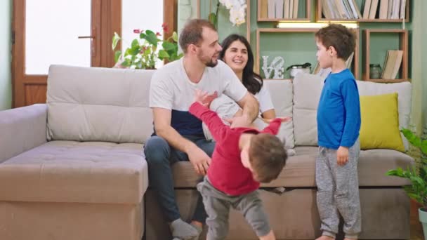 Usmívat se velké a šťastné mladé rodiny se dvěma dětmi a atraktivní rodiče těší čas doma na pohovce si hrají a cítí se skvěle - Záběry, video