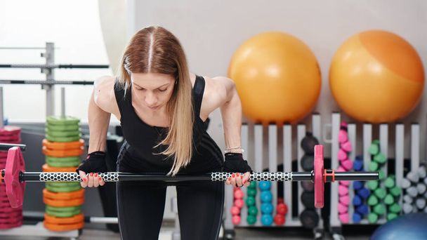 Closeup woman with barbell on group fitness workout with trainer doing body pump exercise in gym - Photo, Image