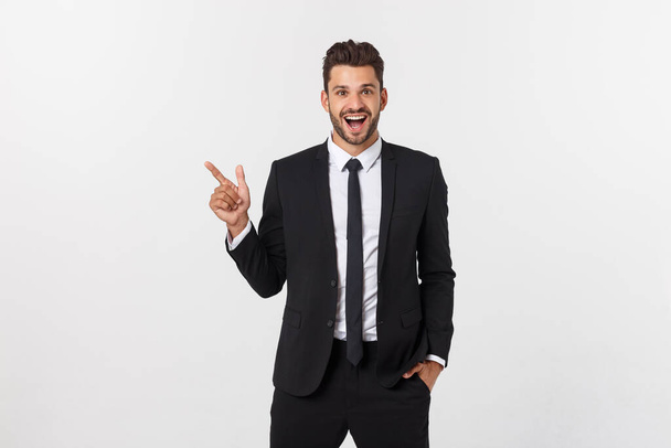 Portrait of young business man in suit pointing at copy space over white background. - Foto, Bild