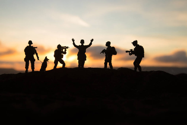 Battle scene. Military silhouettes fighting scene on war fog sky background. A German soldiers raised arms to surrender. Plastic toy soldiers with guns taking prisoner the enemy soldier. Artwork - Photo, Image