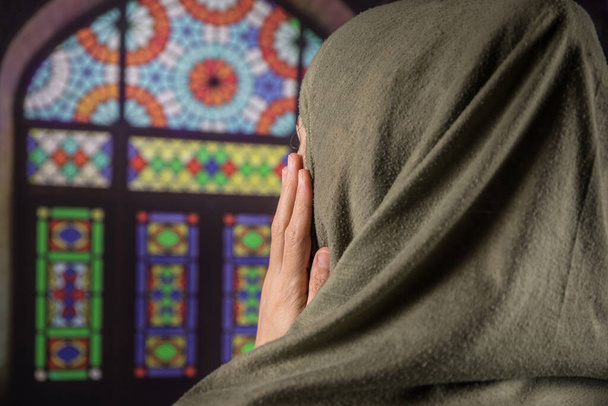 Musliminainen rukoilee Allahin muslimijumalaa moskeijassa. Kädet musliminaisen matolla rukoilee perinteisissä yllään vaatteita, Nainen Hijabissa
. - Valokuva, kuva