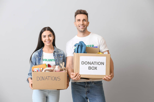 Volunteers with donations for orphans on grey background - Photo, Image