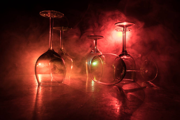 Чаша вина на деревянном столе с красивыми тонированными огнями на заднем плане. Стаканы вина на тёмном фоне. Выборочный фокус. Клубные напитки - Фото, изображение