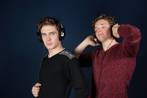 Два привабливих хлопця слухають навушники
. - Фото, зображення