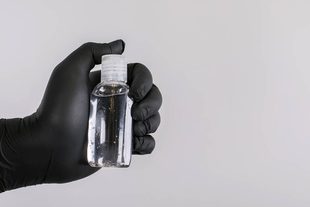 Male hand in black glove holding antibacterial sanitizer hand gel. Coronavirus prevention concept. Copy space - Photo, image