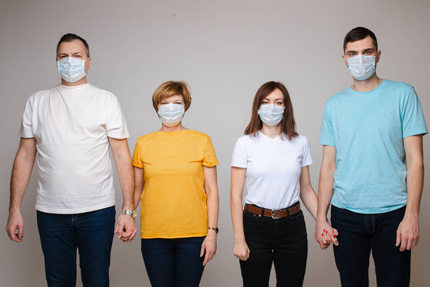 Maskeli dört yetişkin insan virüse karşı birlikte savaşıyor.. - Fotoğraf, Görsel