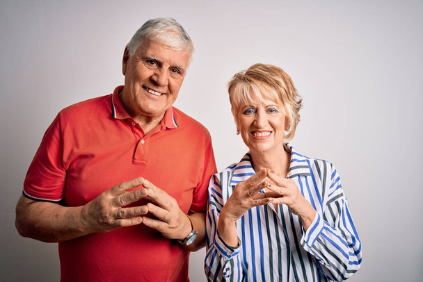 Ältere schöne Paar, das zusammen vor isoliertem weißen Hintergrund Hände zusammen und Daumen drücken lächelnd entspannt und fröhlich. Erfolgreich und optimistisch - Foto, Bild