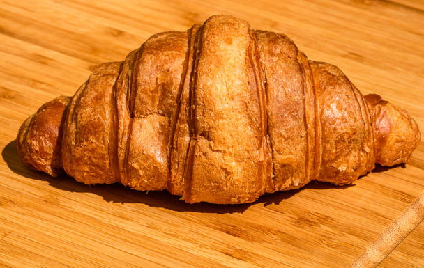 Friss croissant részletek a fa asztalon. Étel és reggeli koncepció. Közelkép a francia vajas croissant - Fotó, kép