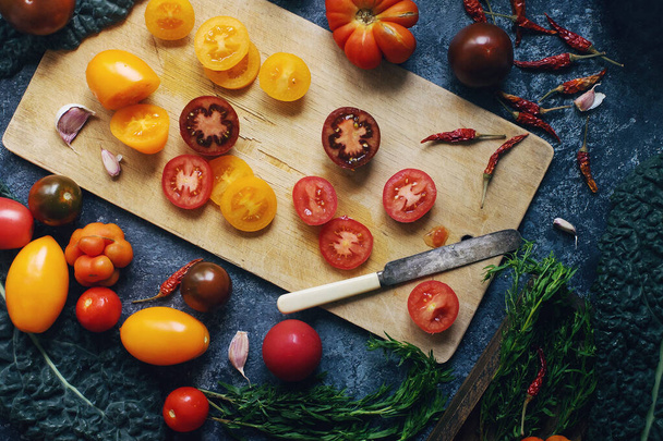 Mix of colorful raw fresh tomatoes and herbs on dark stone table and old wooden board, healthy lifestyle, organic food concept, top view - Fotografie, Obrázek